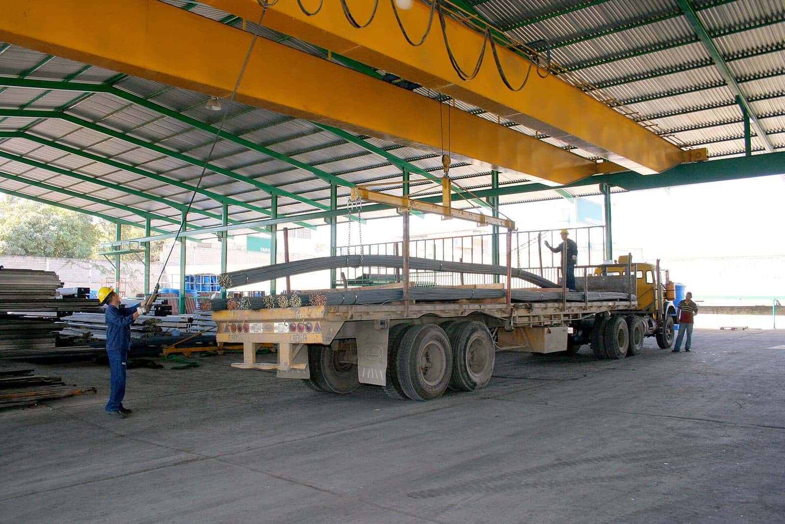 Overhead crane di bengkel fabrikasi mengangkat material dari atas truk